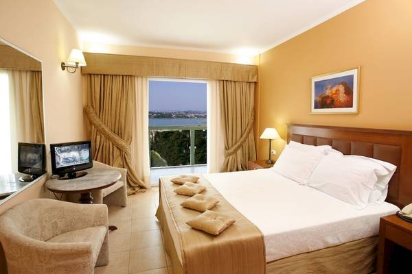 Ariti Grand Hotel Corfu Zimmer mit Bett, Kissen, Tisch, Fernseher und Meerblick.