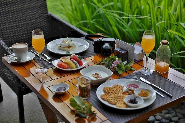 Frühstückstisch im Salinda Resort auf Phu Quoc mit Früchten, Kaffee, Waffeln und Kamera.