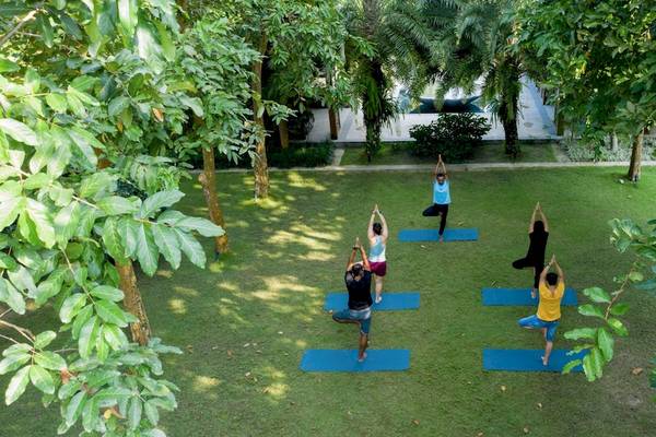 Yoga-Kurs im Garten des Salinda Resort auf Phu Quoc Island mit mehreren Teilnehmern auf blauen Matten.