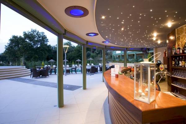 Außenbereich der Poolbar im Ariti Grand Hotel Corfu mit beleuchteter Decke und Tischen.
