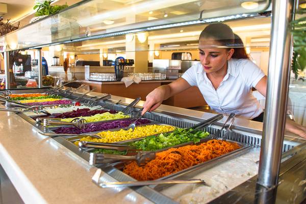 Eine Frau bedient das Buffet im Messonghi Beach Holiday Resort mit verschiedenen Salaten und Beilagen.