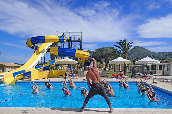 Gruppe macht im Pool Workout mit Wasserrutsche im Hintergrund