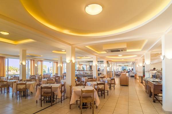 Innenansicht des Restaurants im Messonghi Beach Holiday Resort mit gedeckten Tischen und warmer Beleuchtung.