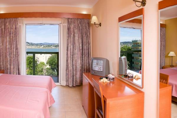 Hotelzimmer im Ariti Grand Hotel Corfu mit zwei Betten, einem Fernseher und einem Balkon mit Meerblick.