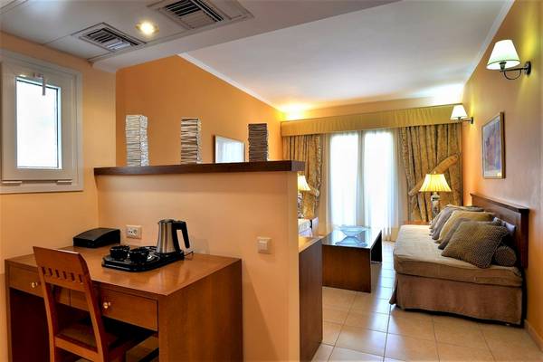 Innenansicht eines Zimmers im Ariti Grand Hotel Corfu mit Schreibtisch, Kaffeemaschine und Schlafsofa.