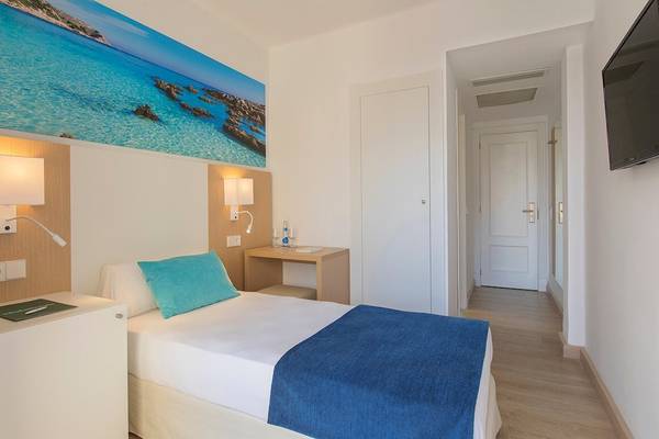 Innenansicht eines Zimmers im Whala Beach Hotel mit Meerblicktapete, Bett, Nachttischen und offenen Türen.