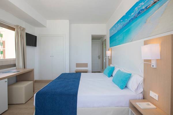 Innenansicht eines Zimmers im Whala Beach Hotel mit Doppelbett, blauer Bettwäsche und weißem Dekor.
