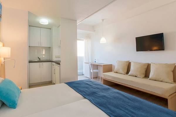 Innenansicht eines Zimmers im Whala Beach Hotel mit Bett, Sofa, Fernseher und Küche.