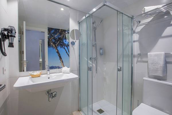 Badezimmer im Whala Beach Hotel mit einer Glasdusche, Waschbecken und Toilette.