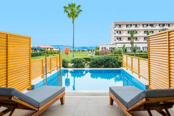 Pool-Terrasse des Mitsis Ramira Beach Hotels mit Lounges und gelben Gittern.