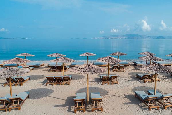 Strandszene mit Liegen und Strohschirmen am Mitsis Ramira Beach Hotel