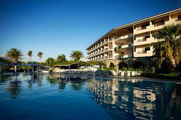 Außenpoolbereich des Mitsis Ramira Beach Hotels mit Sonnenschirmen und Liegestühlen.