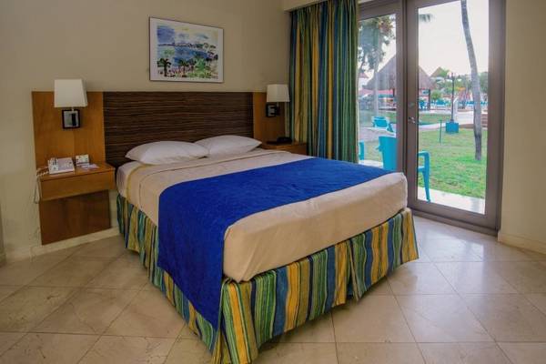 Hotelzimmer im Mill Resort & Suites mit Bett, Tisch, Lampen und Glastür.