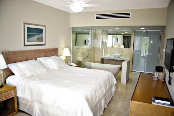 Schlafzimmer im Mill Resort & Suites mit einem großen Bett, Badewanne und Spiegeln.