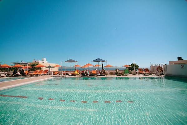 Außenpool des Kosta Palace City Hotel mit Sonnenliegen und Sonnenschirmen an einem sonnigen Tag.