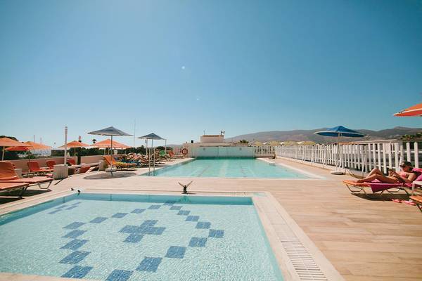 Außenpools des Kosta Palace City Hotel mit Sonnenliegen und Sonnenschirmen.