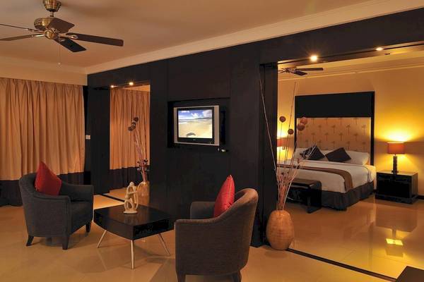Innenansicht eines Zimmers im Le Meridien Ile Maurice Hotel mit Wohnzimmermöbeln, Fernseher und Bett.