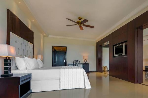 Schlafzimmer im Le Meridien Ile Maurice Hotel mit großem Bett, Fernseher und Deckenventilatoren.
