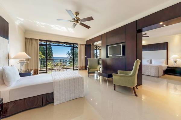 Suite-Zimmer im Le Meridien Ile Maurice mit Blick auf den Ozean und einem Fernseher.