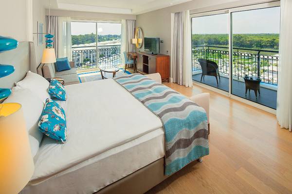 Innenansicht eines Hotelzimmers im Titanic Deluxe Golf Belek mit Blick auf eine Terrasse.