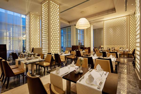 Restaurant im Titanic Deluxe Golf Belek mit eleganten Tischen, Stühlen und floralen Dekorationen.