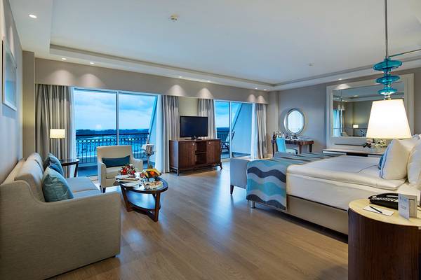 Innenansicht einer Hotelsuite im Titanic Deluxe Golf Belek mit Wohnzimmer, Schlafzimmer, Balkon und Ausblick.