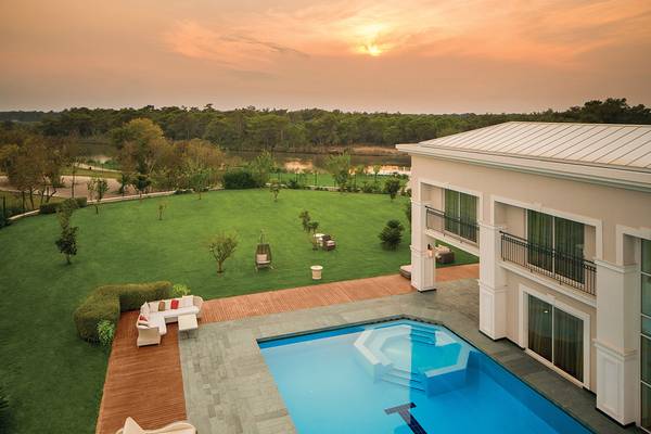 Außenbereich des Titanic Deluxe Golf Belek Hotels mit Pool und Blick auf den Sonnenuntergang.