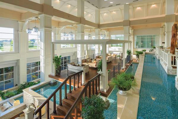 Innenansicht des Titanic Deluxe Golf Belek Hotels mit Swimmingpool, Loungebereich und Holztreppen.