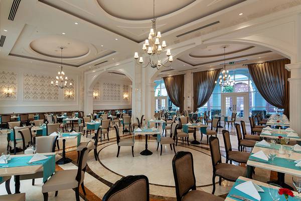 Innenansicht des Restaurants im Titanic Deluxe Golf Belek Hotel mit runden Tischen und Stühlen.
