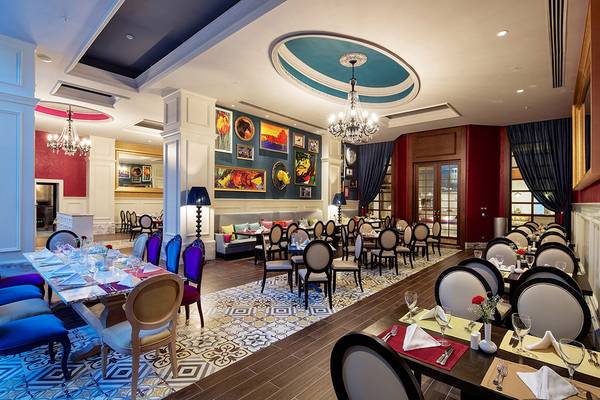 Innenansicht des Restaurants im Titanic Deluxe Golf Belek Hotel mit Tisch, Stühlen und Gemälden an der Wand.