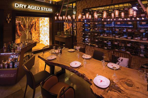 Restauranttisch mit sechs Stühlen, vor dem Schild Dry Aged Steak