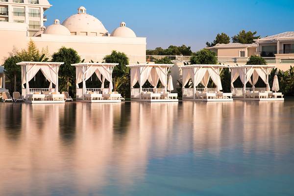 Pool-Lounge-Bereich im Titanic Deluxe Golf Belek Hotel mit weißen Sonnenschirmen und Liegen.