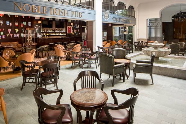 Innenansicht des Noble Irish Pub mit Lederstühlen, Tischen und einer Bar.
