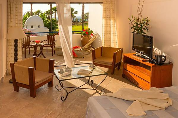 Innenansicht einer Suite im Azia Resort & Spa mit Balkon, Wohnzimmermöbeln und Meerblick.