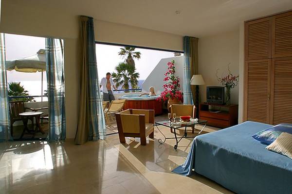 Hotelsuite mit Blick auf einen Whirlpool auf dem Balkon und einem komfortablen Bett