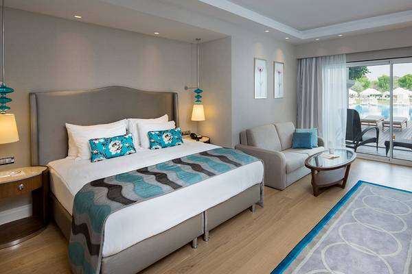 Hotelzimmer im Titanic Deluxe Golf Belek mit großem Bett, Wohnzimmerbereich und Zugang zum Pool.