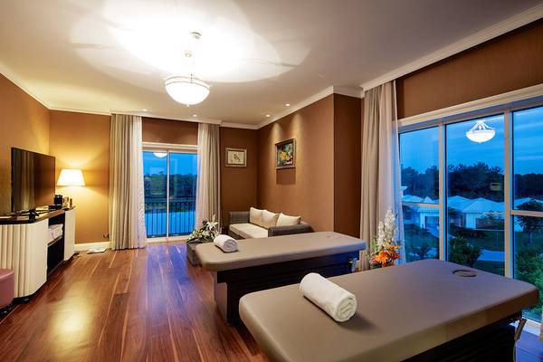 Massageraum im Titanic Deluxe Golf Belek Hotel mit zwei Massagetischen, einem Sofa und einem Fernseher.
