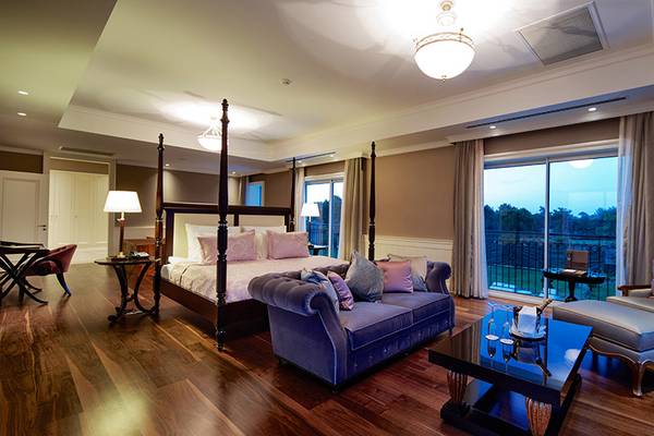Luxuriöses Schlafzimmer im Titanic Deluxe Golf Belek mit großem Bett, Couch, Tisch und großem Fenster.