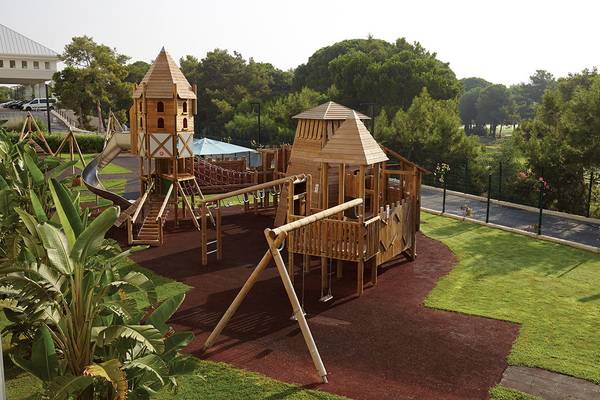 Kinderspielplatz im Titanic Deluxe Golf Belek mit Holztürmen, Rutsche und Schaukeln.