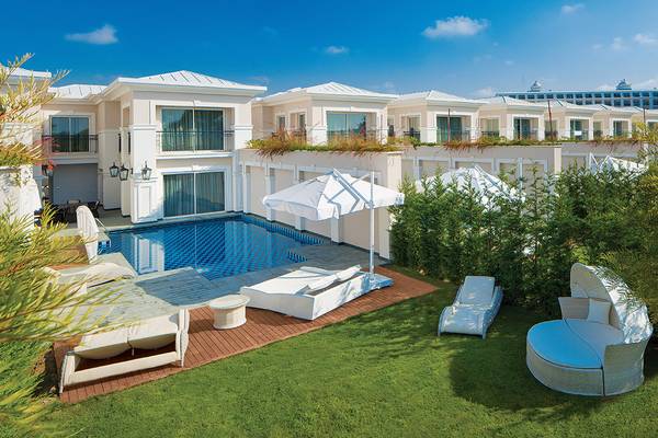 Poolbereich des Titanic Deluxe Golf Belek Hotels mit weißen Liegen und Sonnenschirmen.