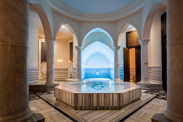 Innenansicht des Pools im Titanic Deluxe Golf Belek Hotel mit Marmorsäulen und blauer Beleuchtung.