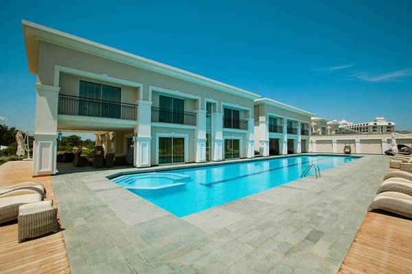 Außenbereich des Titanic Deluxe Golf Belek Hotels mit Swimmingpool und Liegestühlen.