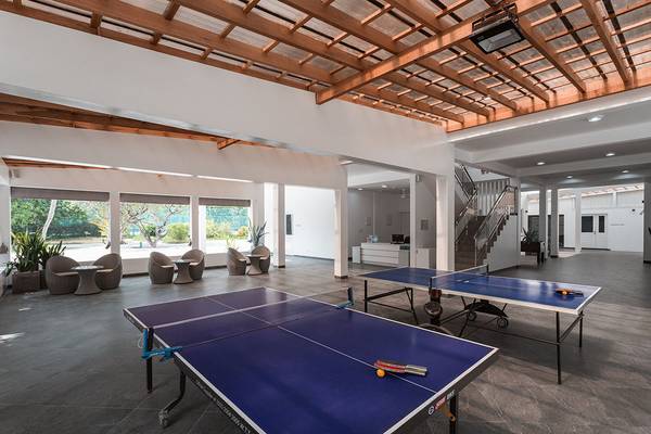 Ping-Pong-Raum im Bandos Maldives Hotel mit zwei Tischen und braunen Stühlen.