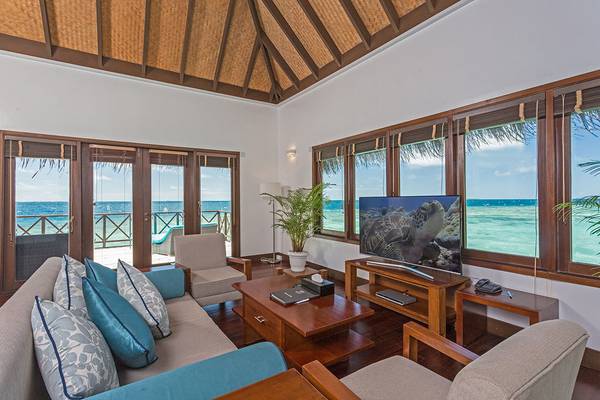 Wohnzimmer im Bandos Maldives Hotel mit Blick auf das Meer und eine Terrasse.