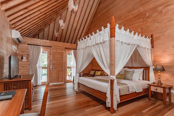 Innenansicht eines Zimmers im Bandos Maldives Hotel mit einem Bett, das von einem Baldachin umgeben ist.