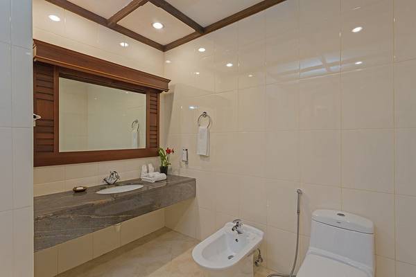 Ein Badezimmer im Bandos Maldives Hotel mit weißem Waschbecken, Bidet, Toilette und Spiegel.