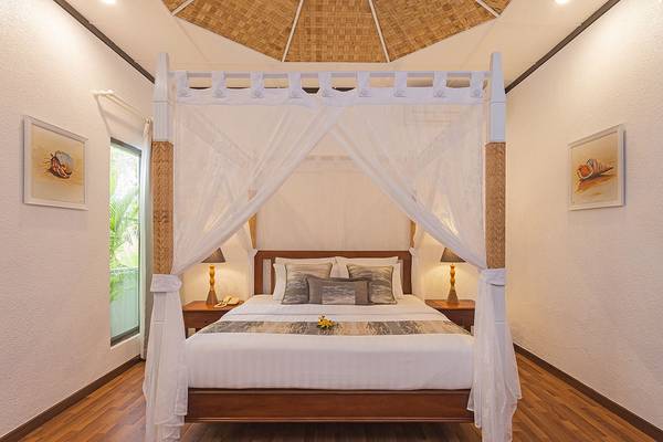 Schlafzimmer im Bandos Maldives Hotel mit Himmelbett, weißen Laken und Kissen.
