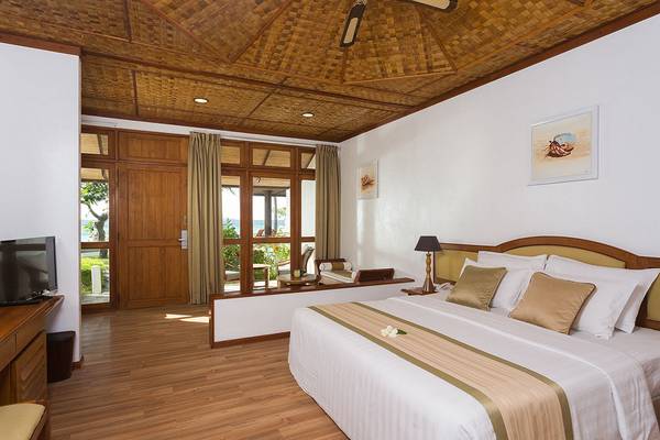 Schlafzimmer im Bandos Maldives Hotel mit Meerblick, Holzboden und Panoramafenstern.