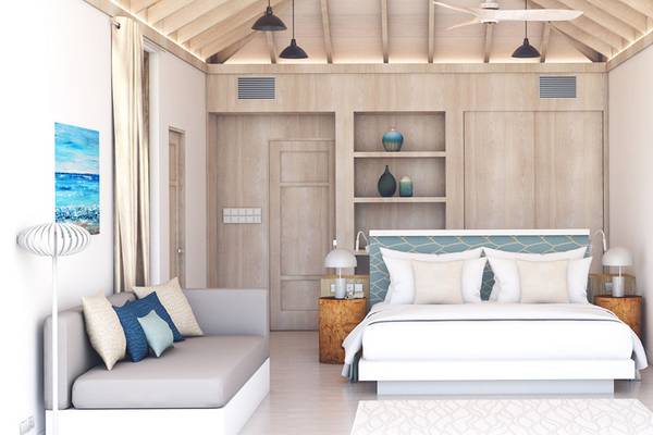 Innenansicht des Schlafzimmers im Bandos Maldives Hotel mit Bett, Sofa, Nachttischen und Deckenventilator.