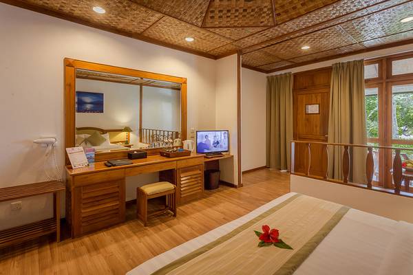 Innenansicht eines Zimmers im Bandos Maldives Hotel mit Doppelbett, Schreibtisch und Fernseher.
